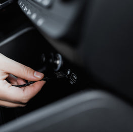 Person using a smartphone inside a car with a focus on the hands and phone.